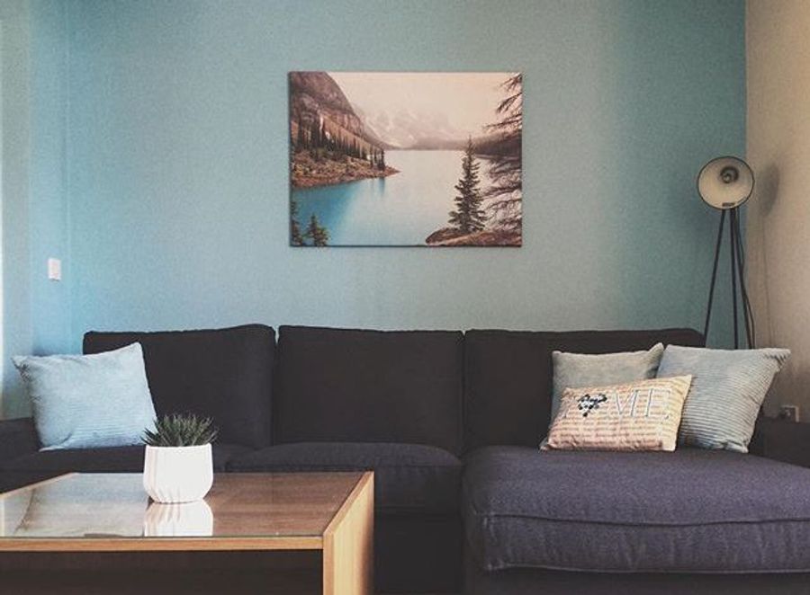 Toile photo d'un paysage de lac de montagne dans un salon bleu avec canapé
