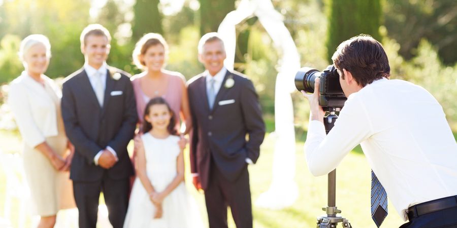 Photographe à un mariage qui prend en photo la famille et les demoiselles d'honneur
