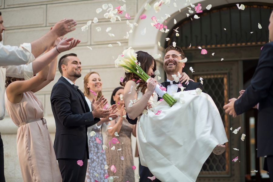 Couple de mariés à la sortie de l'église sous les confettis lancés par la foule des invités