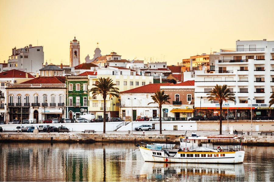 Photo d'un port de l'Algarve au coucher du soleil, avec un petit bateau au premier plan. 