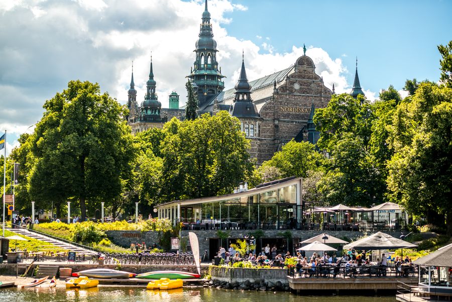  Photo du bâtiment Nordiska à Stockholm face à un café, prise depuis la berge. 